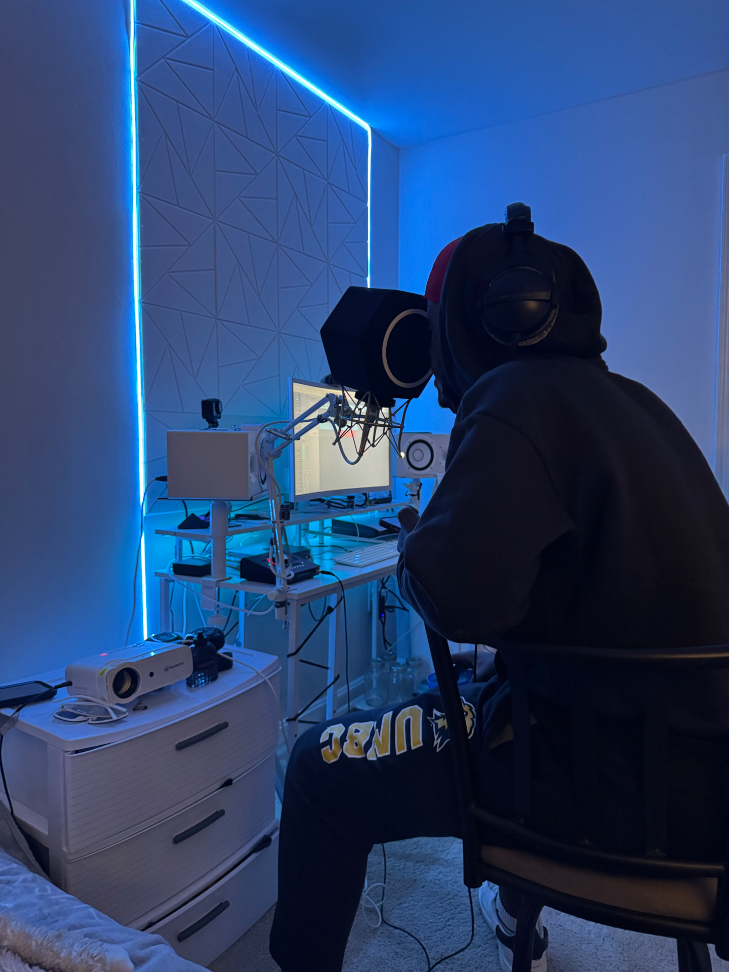 Artist tracking vocals under neon blue LED lighting at Chrome Collaborations DMV studio